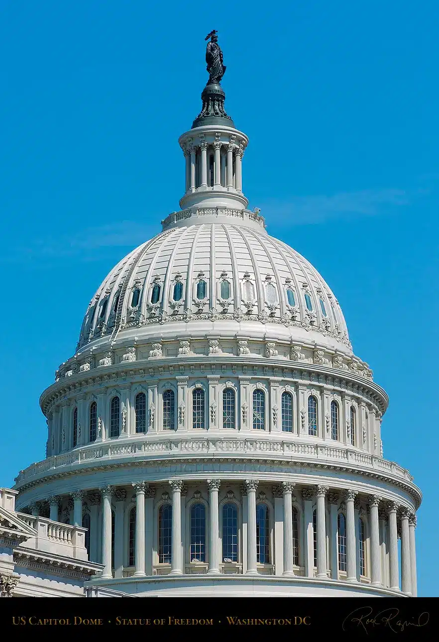 The U.S. Capitol dome with the Statue of Freedom on top against a blue sky.