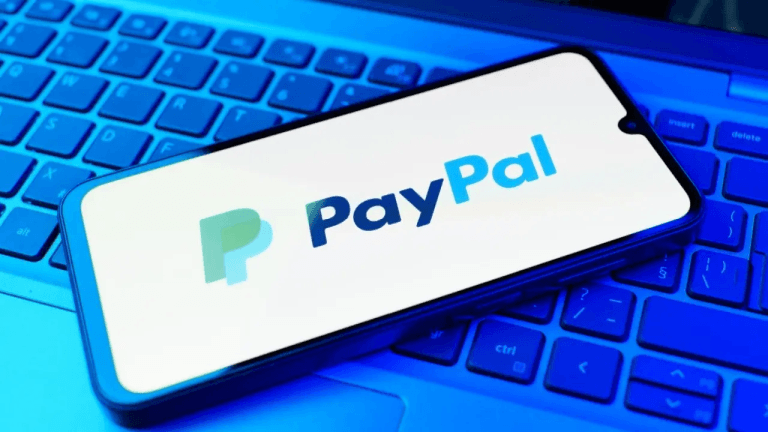 Paypal logo on a phone sitting on a keyboard.